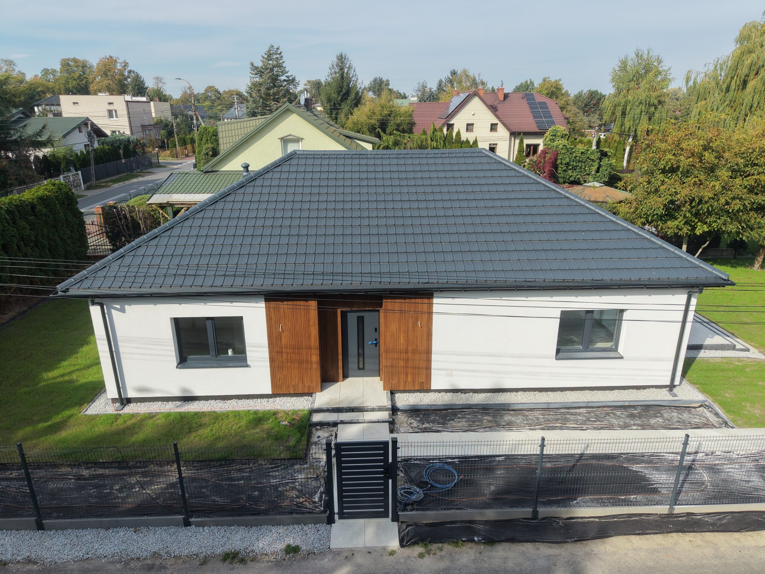 Parterowy dom 111 m² z dachem kopertowym i drewnianym wykończeniem wejścia – widok z drona